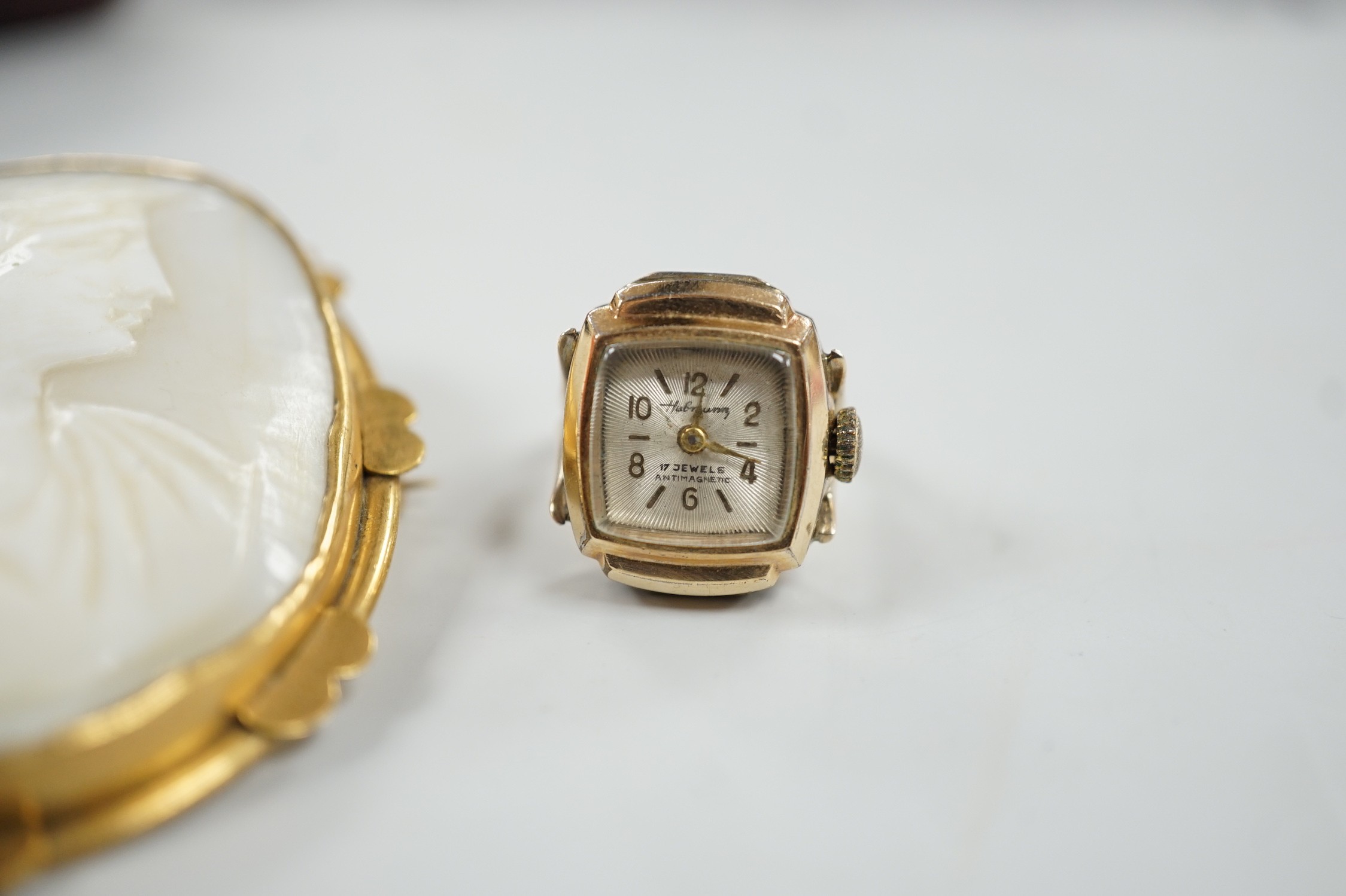 A pinchbeck mounted oval cameo shell brooch, 64mm and a gold plated watch ring.